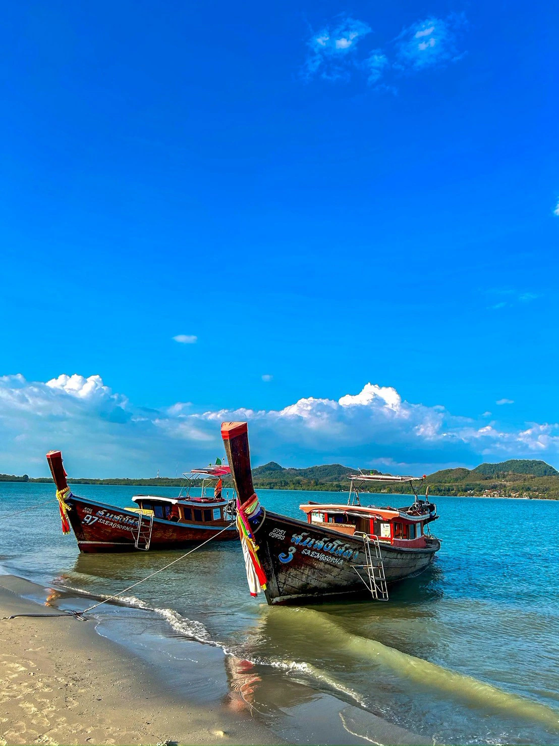 เรือหางยาวสองลำเทียบชายหาดริมทะเลอันดามันใต้ท้องฟ้าสีคราม