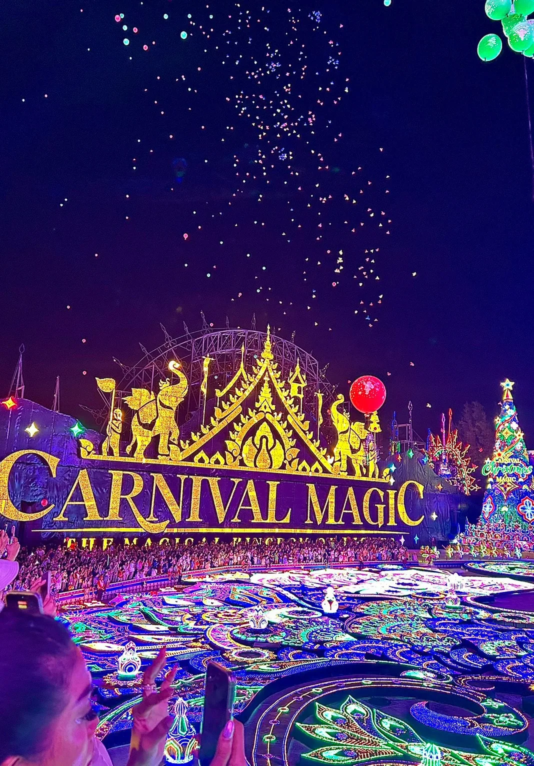 ป้าย Carnival Magic เรืองแสงสีทองและลานไฟนกยูงยามค่ำคืน